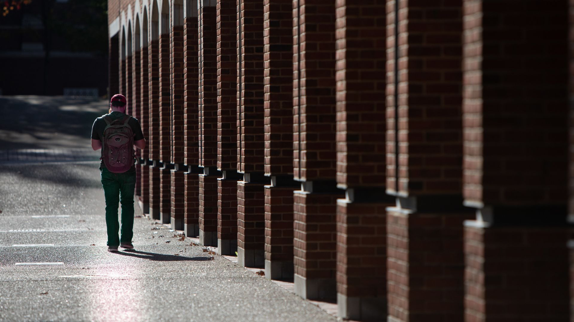 Man walking beside brick building