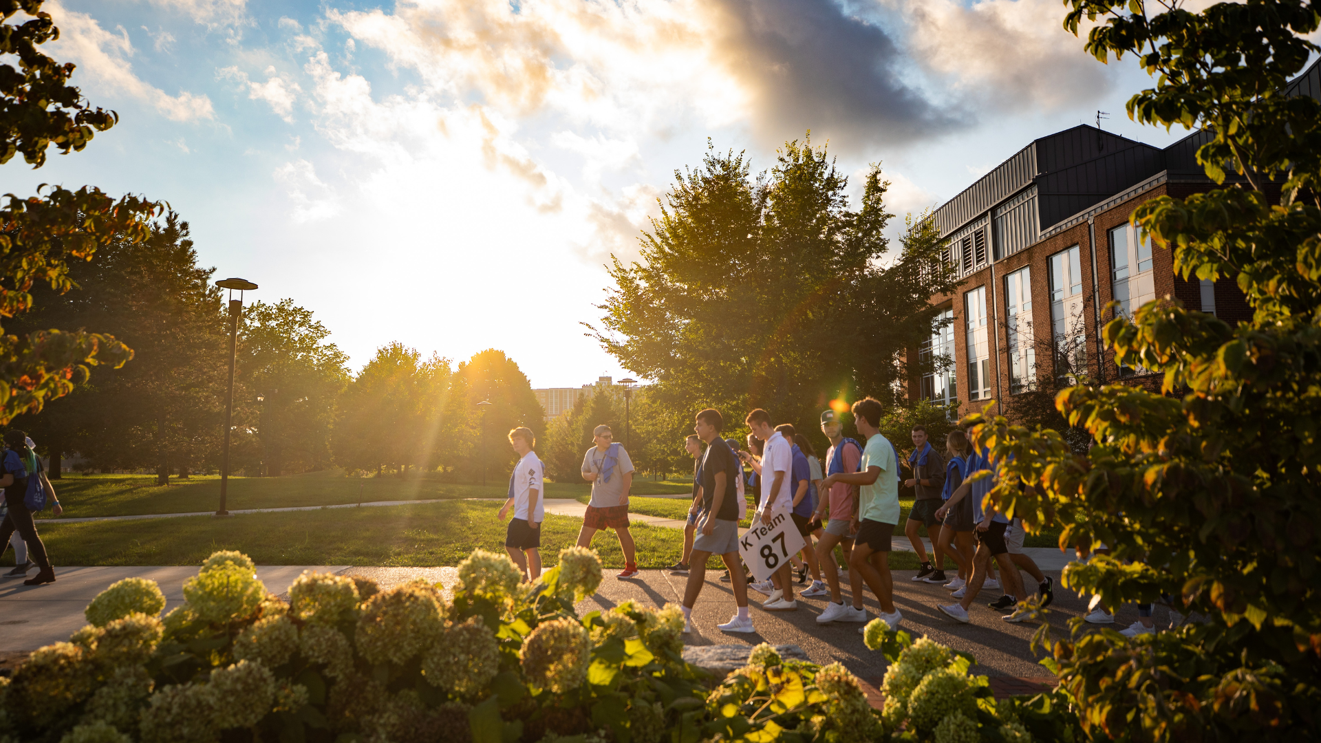 Students walking on campus with sunlight behind them