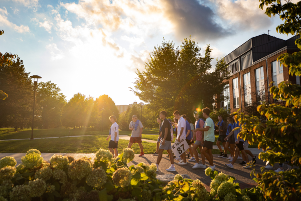 Students walking on campus with sunlight behind them