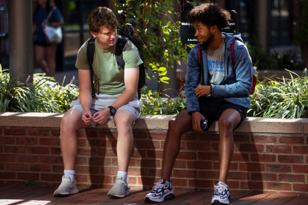 Two students sitting outside on a brick ledge