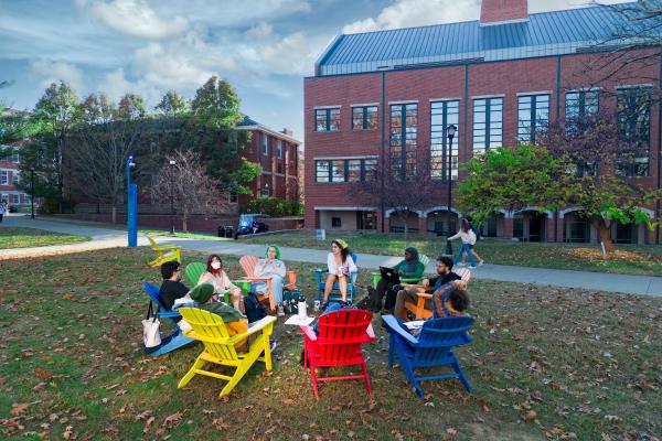 Students sitting in a circle in Adirondack chairs outside