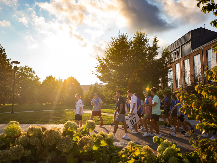Students walking on campus with sunlight behind them