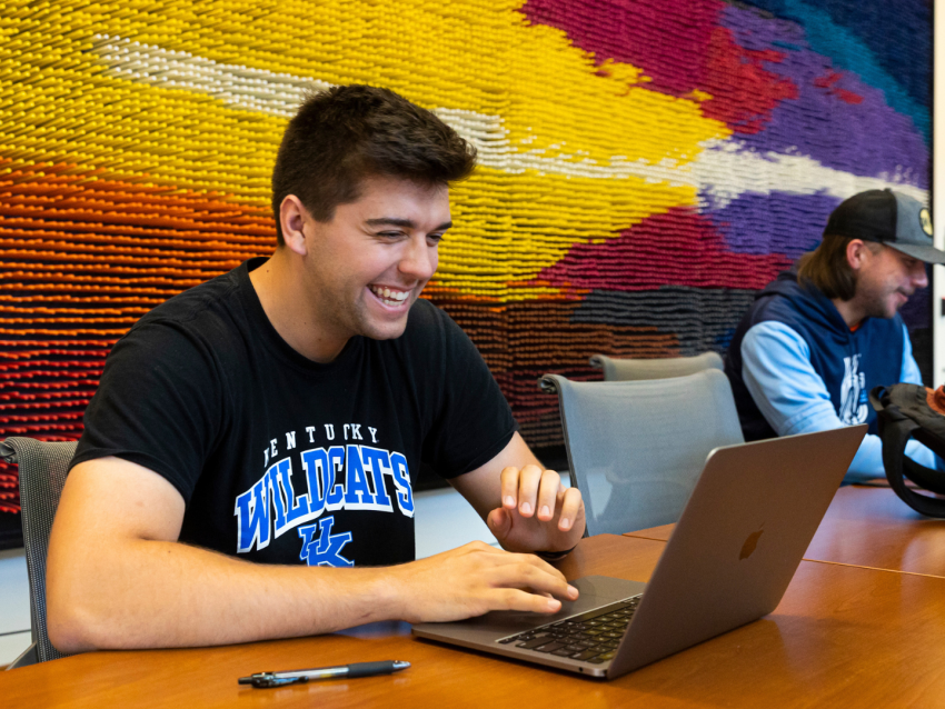 student laughing and looking at laptop on table