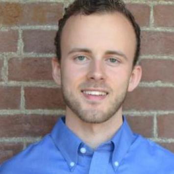 Tyler Russell headshot in front of brick wall