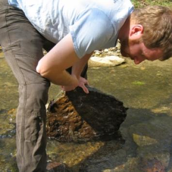 Paul Hime examining large rock in water