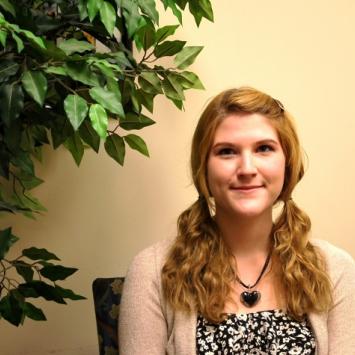 Sarah Gooch sitting in chair beside tree