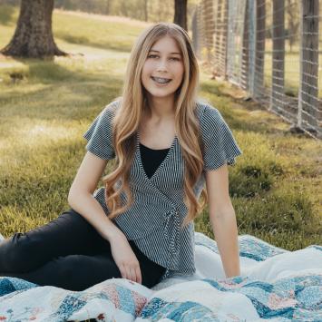 Photo of Hailey Stokes outside sitting on quilt