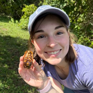 Evie Cecil outside holding a bug