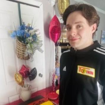 Eli Smith standing by a table with balloons and flowers